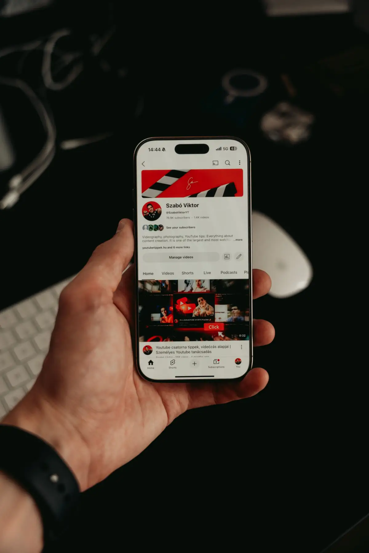 Hand holding a smartphone displaying a dark mobile app interface